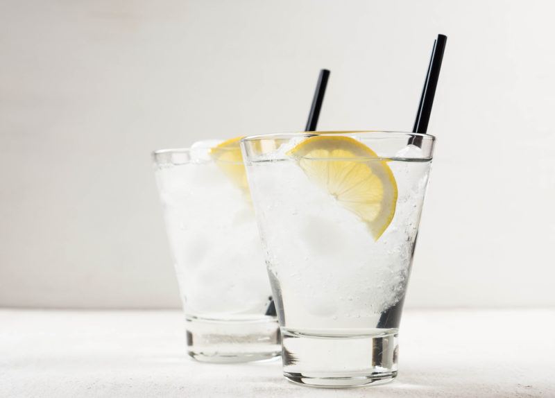 Two clear Kamikaze cocktails in glasses with ice, a lemon slice and a straw