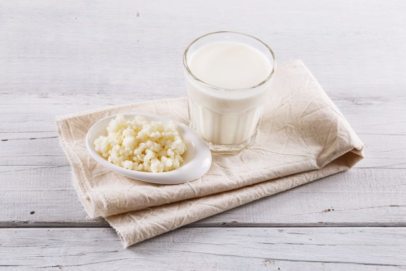 A glass of kefir with kefir grains on a cloth