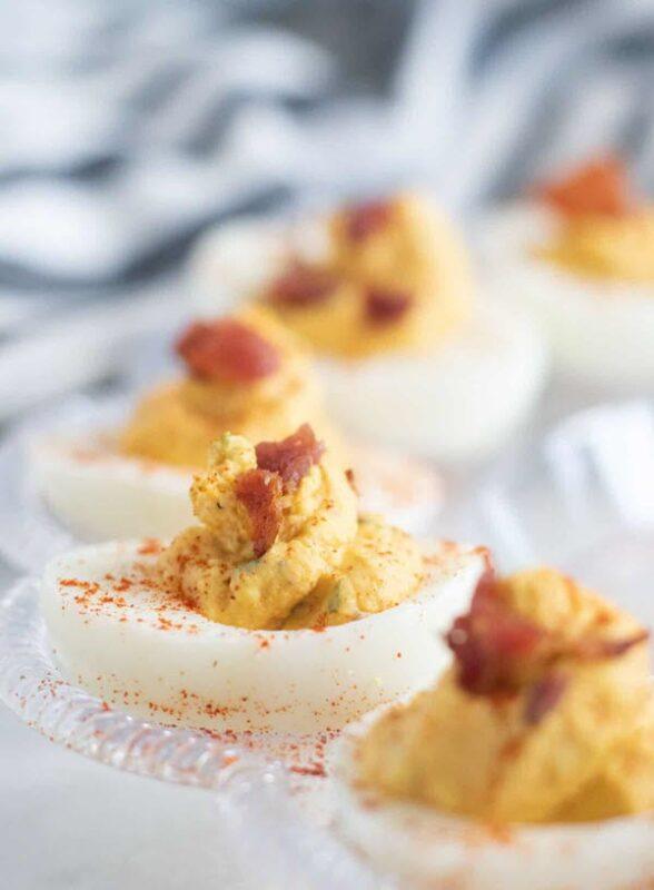 A circular dish with deviled eggs that have been garnished with bacon