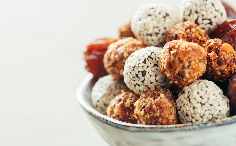 Several types of keto fat bombs rest in a bowl against a white background.