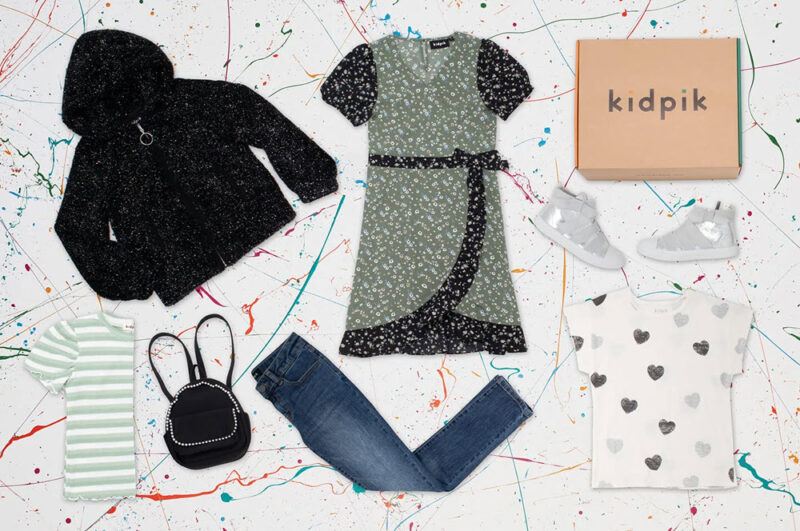 A selection of Kidpik clothing laid out against a white background with colorful detailing