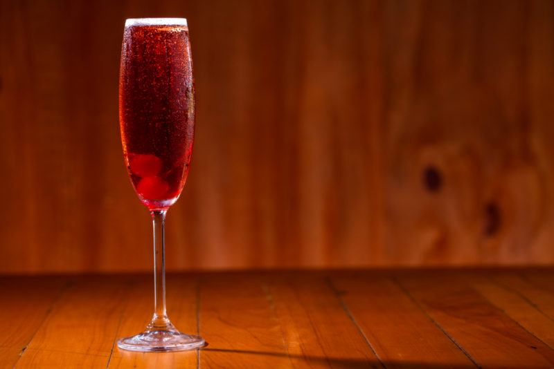 A kir royale cocktail on a wooden table against a wooden background