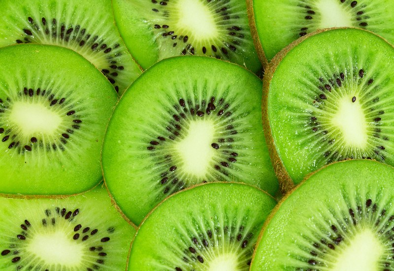 This photo shows a closeup of several slices of green kiwi.