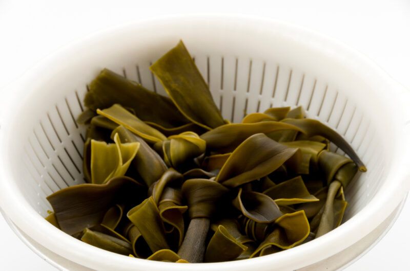 a closeup image of a white plastic colander with kombu