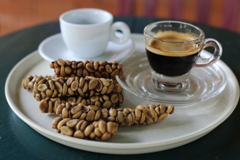 A white plate with two mugs of coffee and kopi luwak coffee beans