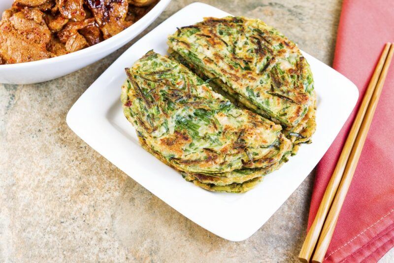 A white plate on a table with a small stack of Korean green onion pancakes