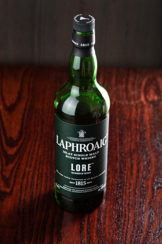 Laphroaig Lore whisky bottle on dark wood table