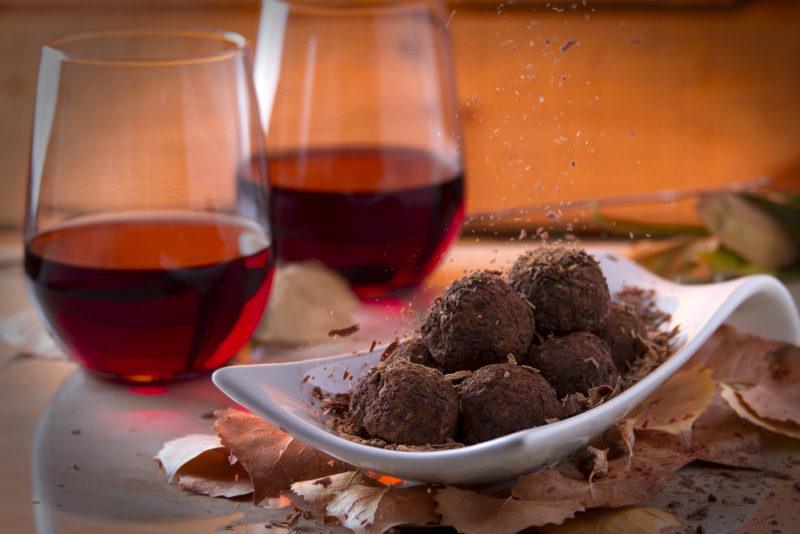 Two stemless glasses of red wine and a white dish with truffles