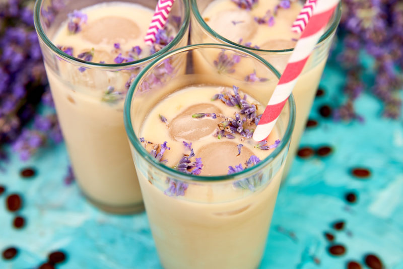 Three lavender honey cream cocktails in glasses with straws