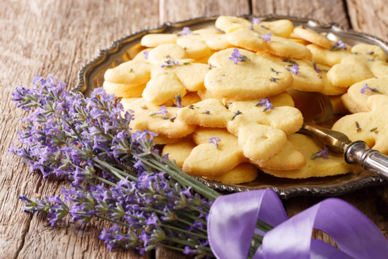 A metal tray of shortbread with lavender, next to stalks of lavender