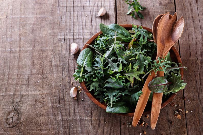 A bowl of leafy greens with utensils