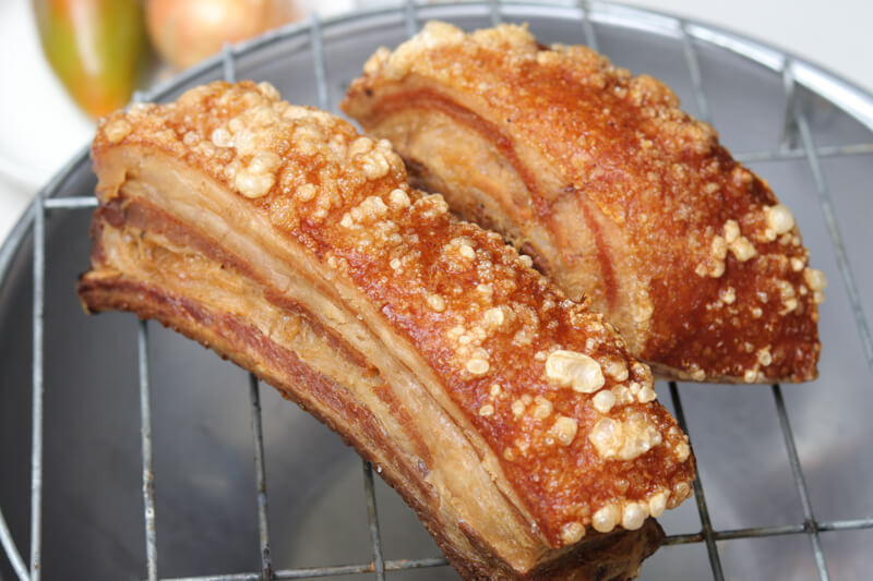 A draining rack with two perfectly cooked pieces of pork belly