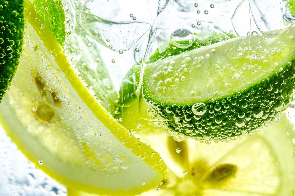 A close up image of soda water with lemon and lime pieces