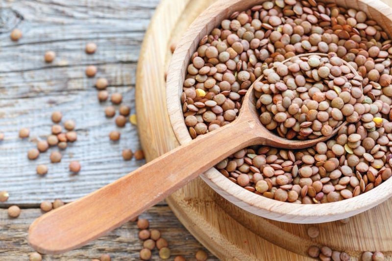 A wooden bowl and spoon filled with lentils