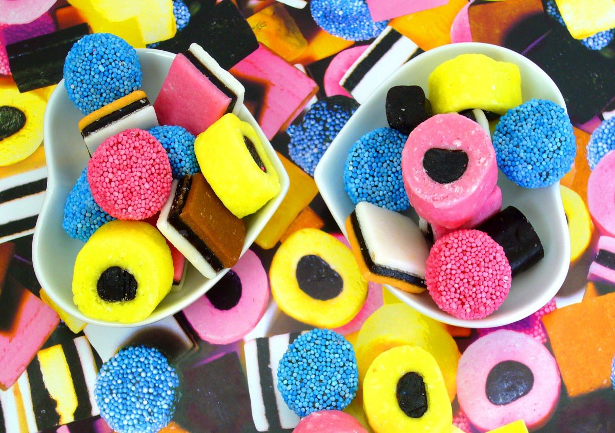 Bright colored assorted licorice candies with two heart shaped bowls in the center of the photo both bowls also are full of licorice