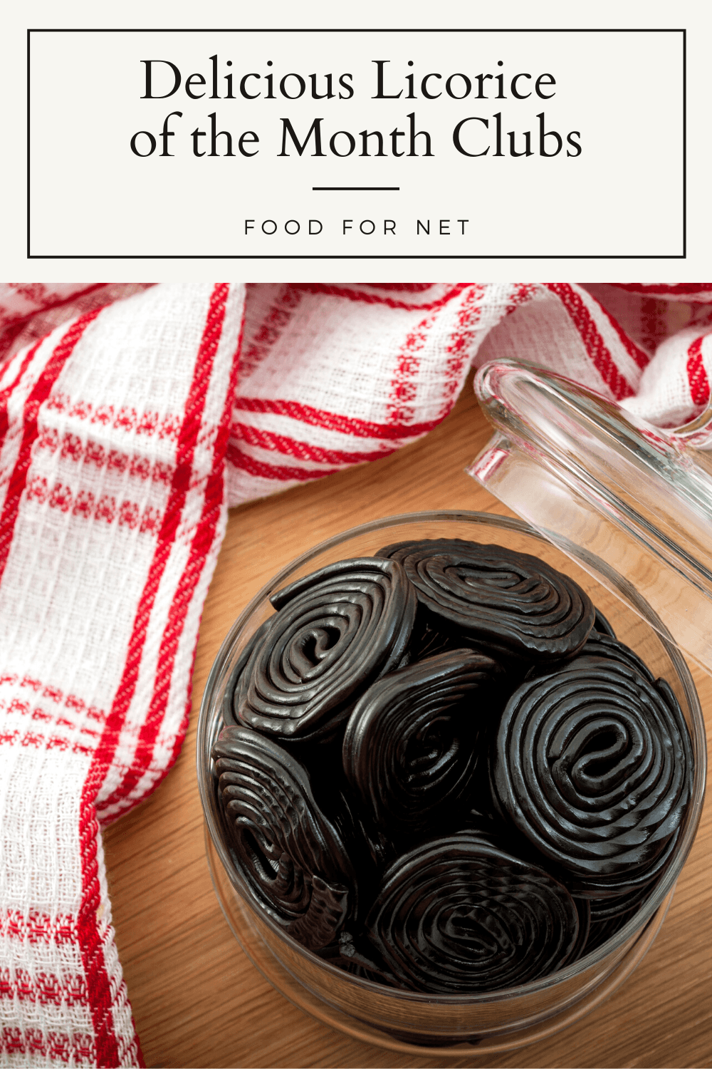 A glass bowl of licorice rounds on a wooden table with a red and white cloth