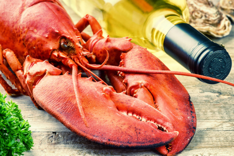 A boiled lobster on a table next to a bottle of chardonnay