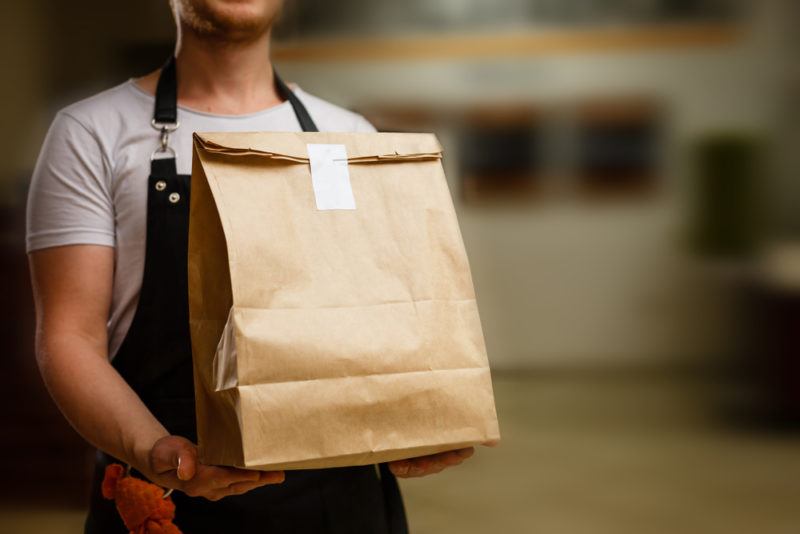 A man holding a paper bag of food