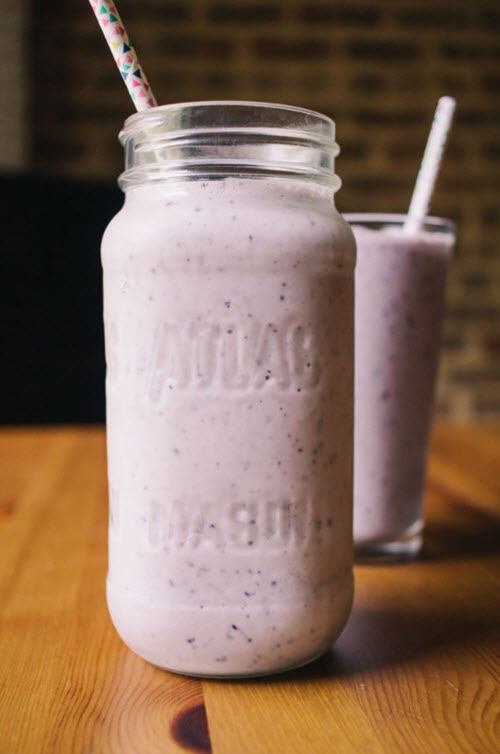 A large and a small glass of a light colored blueberry smoothie