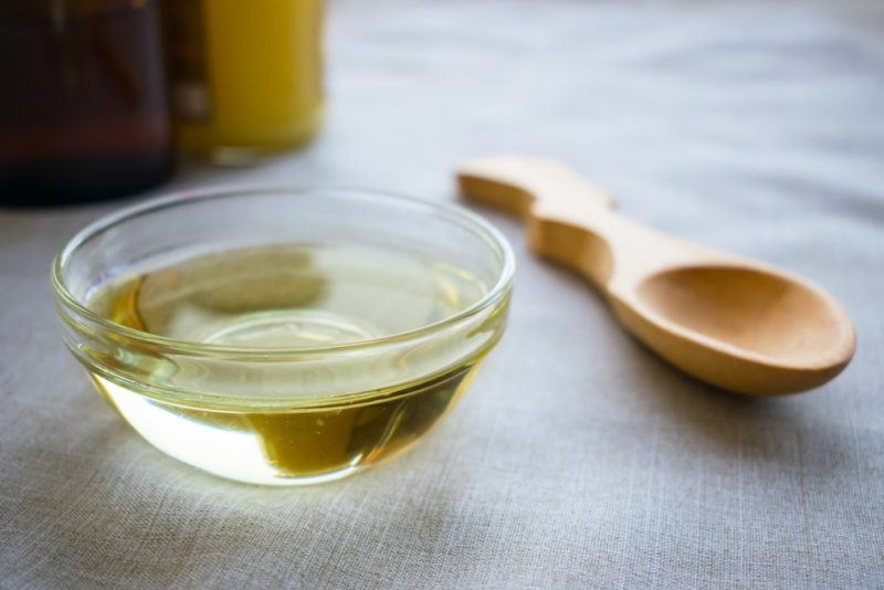 MCT oil in a glass bowl with a wooden spoon