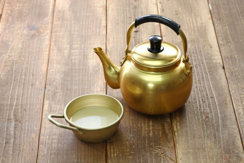 A copper jug containing makgeolli and a mug