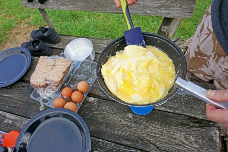 Using a frypan over a table to make an omelet, with various ingredients on the table