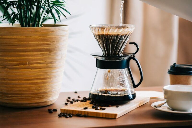 A glass container with coffee being made using a drip tool