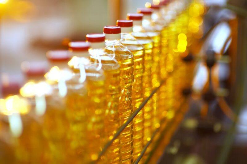 A line of many vegetable oil bottles with red caps