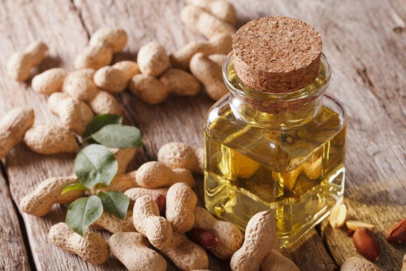 A table with many peanuts, next to a bottle of peanut oil