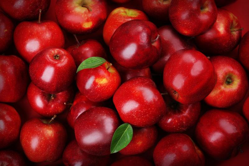 A selection of bright red apples with a few leaves all piled together