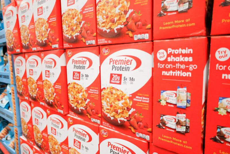 Many red boxes in a grocery store containing Premier Protein cereal