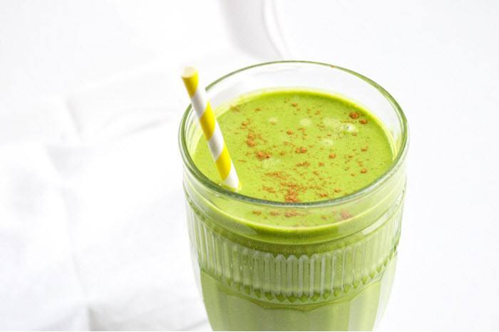 A green smoothie in a glass against a white background