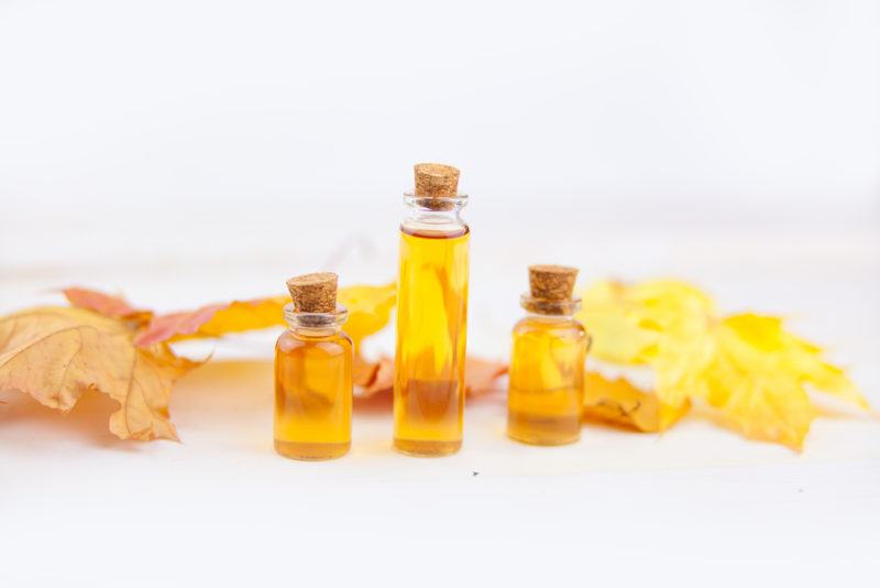 Three bottles of maple extract with maple leaves in the background