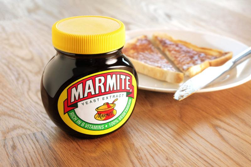 A jar of marmite with marmite on toast in the background