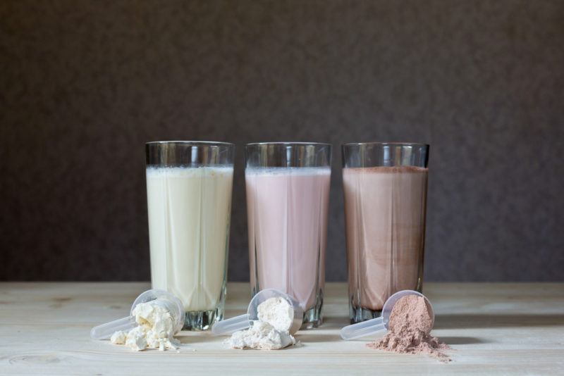 Three classes of meal replacement shakes with a scoop of protein powder in front of each glass