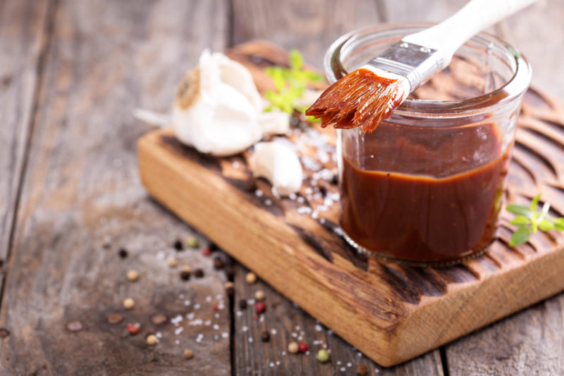 A glass of brown marinade for meat on a wooden board