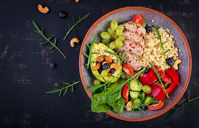 A bowl that contains bulgar, meatloaf, avocado and greens