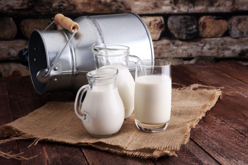 Three jugs of milk with a milk carton in the background