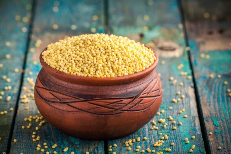 A wooden bowl of millet on a blue table