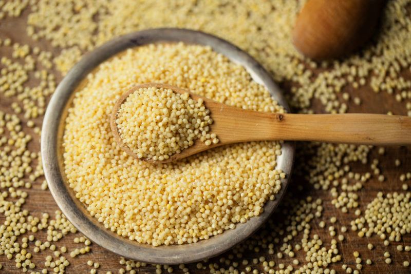 A bowl of millet witha spoon on a table