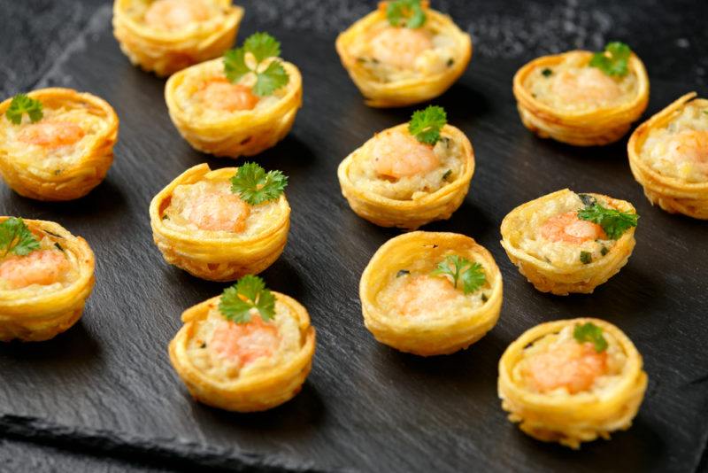 A black dish with a large number of mini fish pies