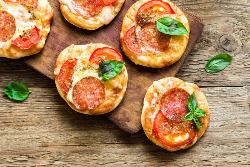 Mini pizzas on a wooden board that have been made on biscuits