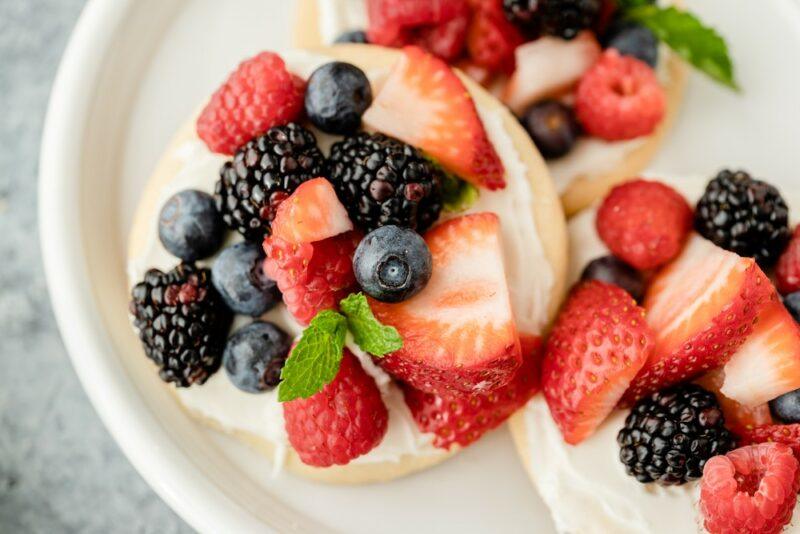 Sugar cookie fruit pieces with a cream cheese layer and plenty of fresh berries