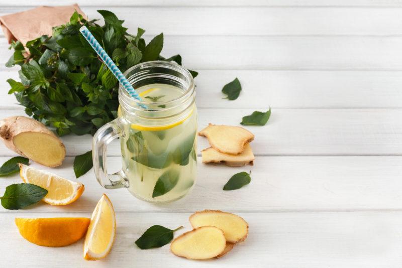 A mason jar glass of mint and ginger lemonade on a wooden table