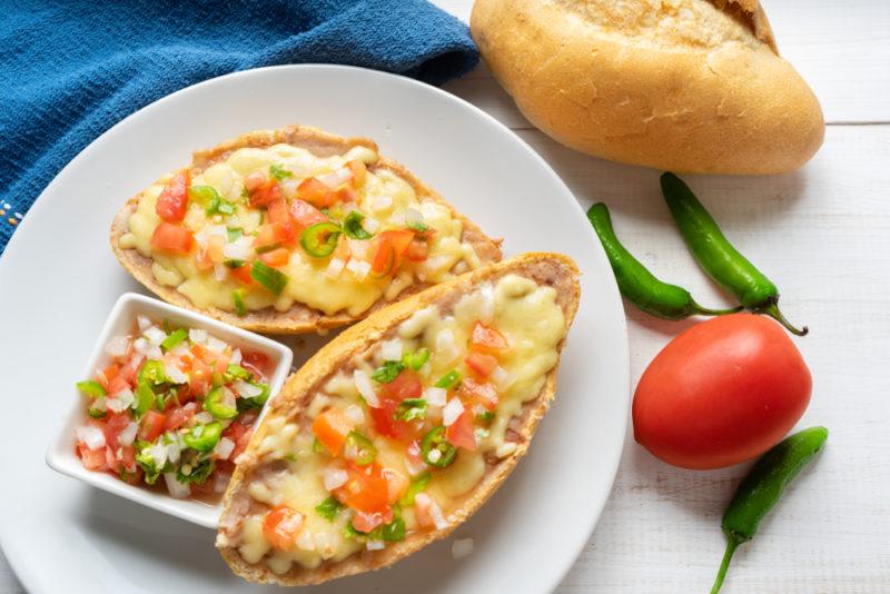 Two molletes, which are similar to a Mexican breakfast pizza, served on a roll or something similar