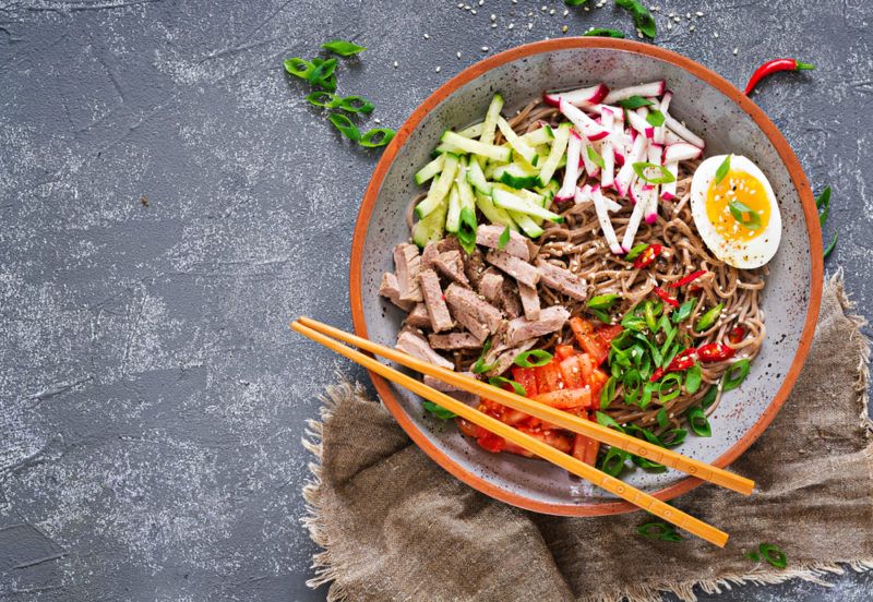 A bowl with buckwheat noodles, chopsticks and eggs