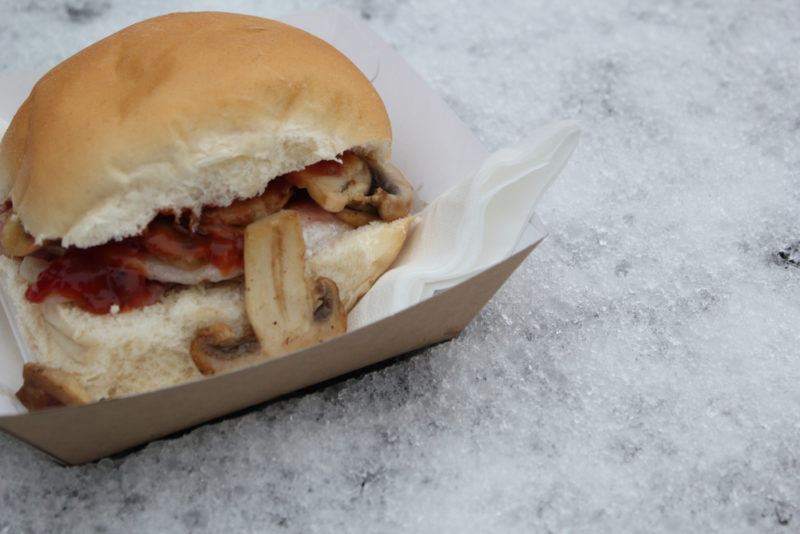 A morning roll with bacon and other ingredients on a paper plate