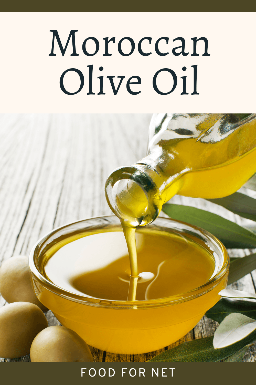 Moroccan olive oil being poured from a bottle into a glass bowl, near some olives and olive leaves