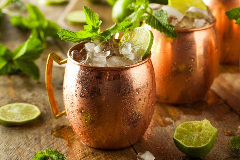 Two Moscow Mule cocktails in copper mugs on a wooden table