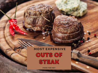 A wooden board with two cooked pieces of filet mignon, a knife and fork, plus some herbed butter, highlighting the most expensive cuts of steak